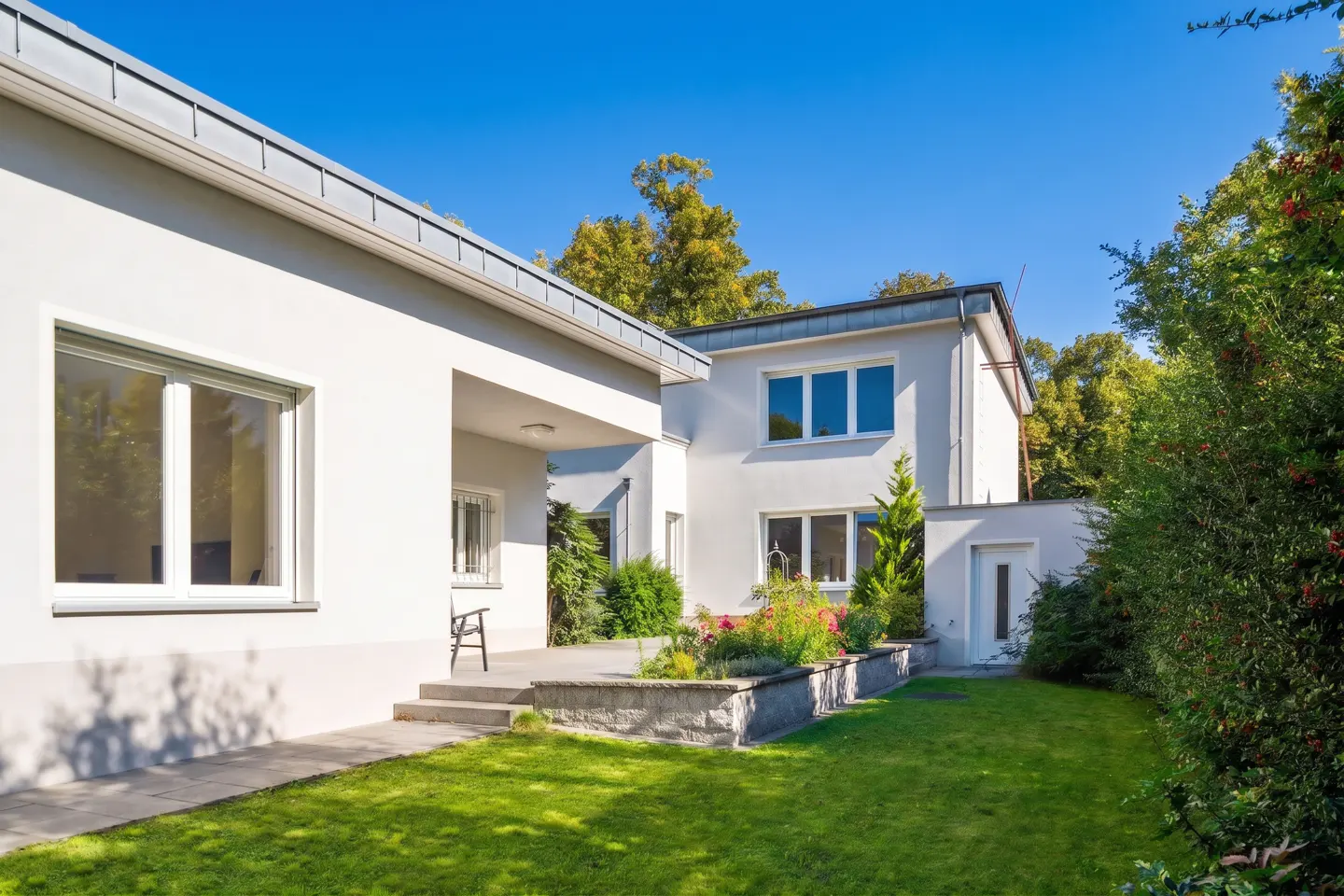 Exterior of a modern white house with a green lawn and blue sky.