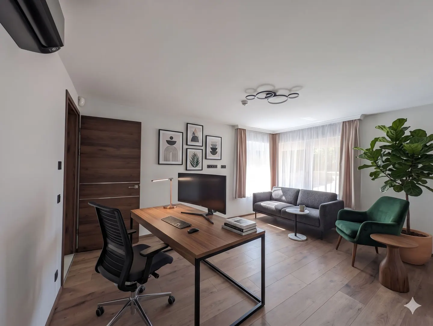 Bright living space with a wooden desk, black chair, gray sofa, and green armchair. Artwork adorns the wall above a large monitor.