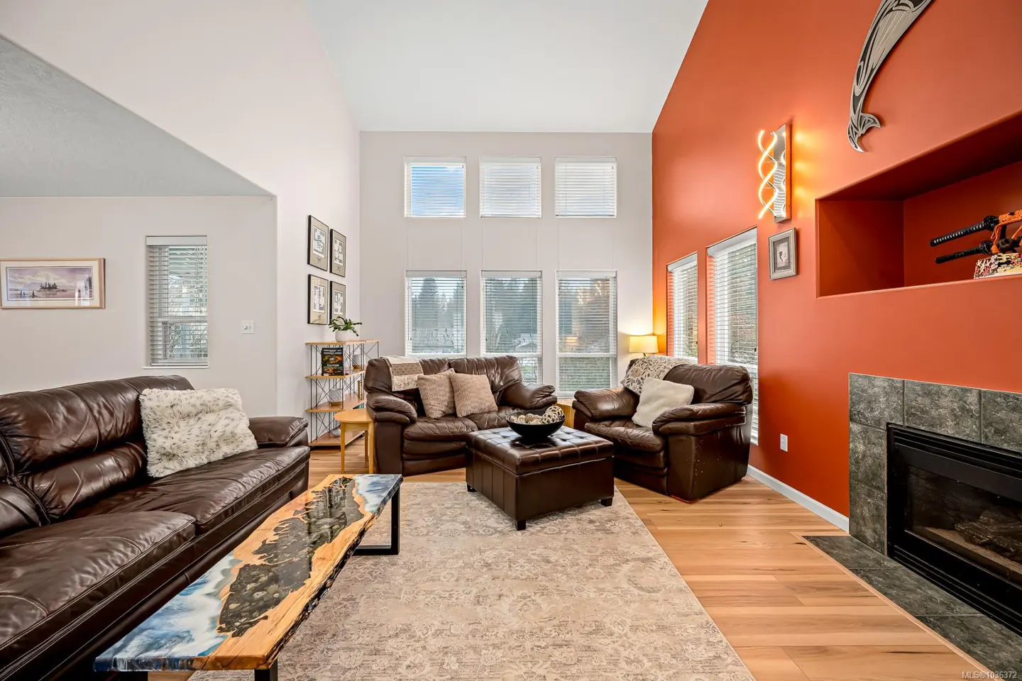 Living room with brown leather sofas, a unique coffee table, and an orange accent wall with a fireplace.
