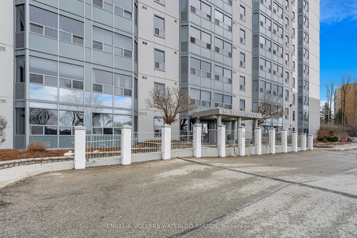 Exterior shot of "55 The Westview" apartment building with gray facade, large windows, and white fence.