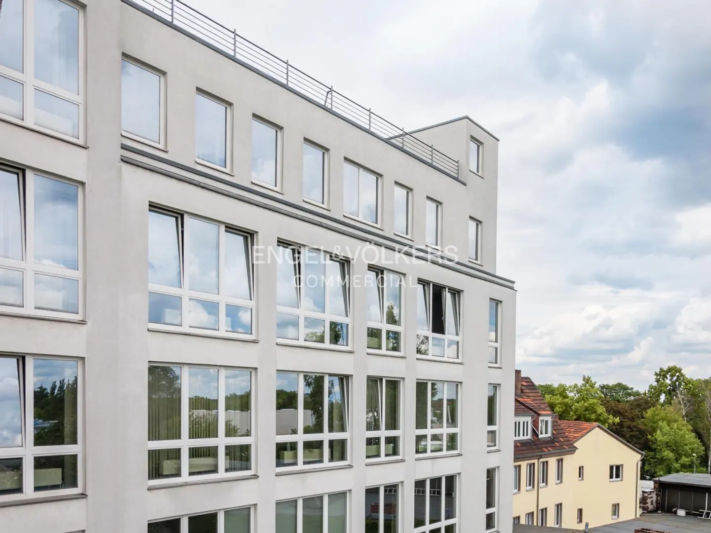 Exterior view of a modern, multi-story commercial building with large windows and the Engel & Völkers logo.