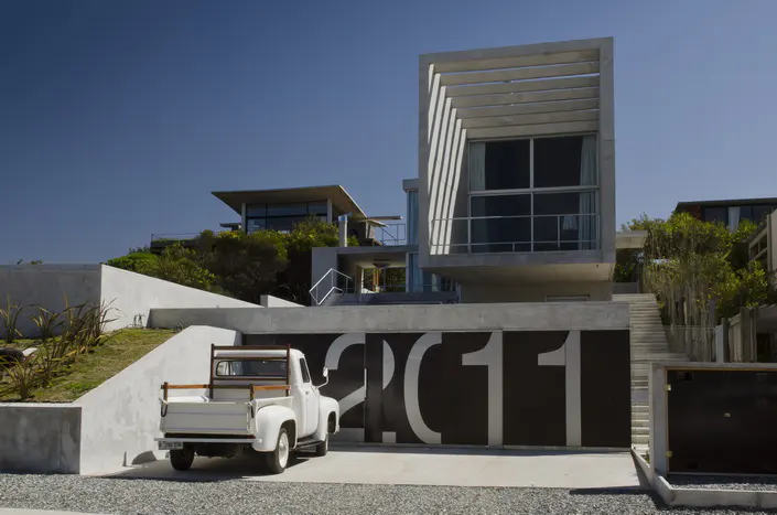 Modern concrete house with a white vintage truck parked in front of a garage door with the number 2011.