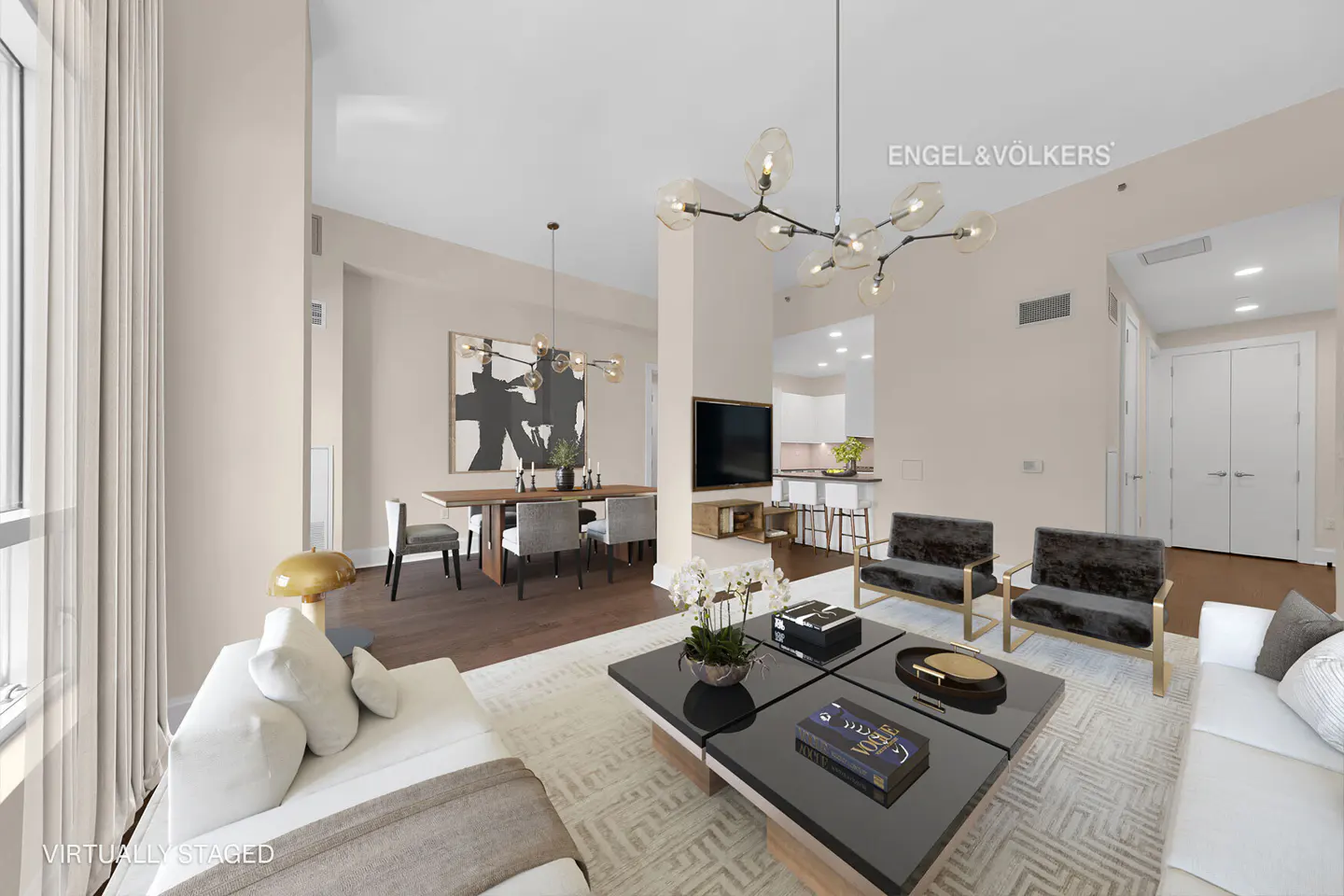 Open-concept living and dining area with white sofas, black coffee table, and dining table with gray chairs. Modern light fixtures hang above.