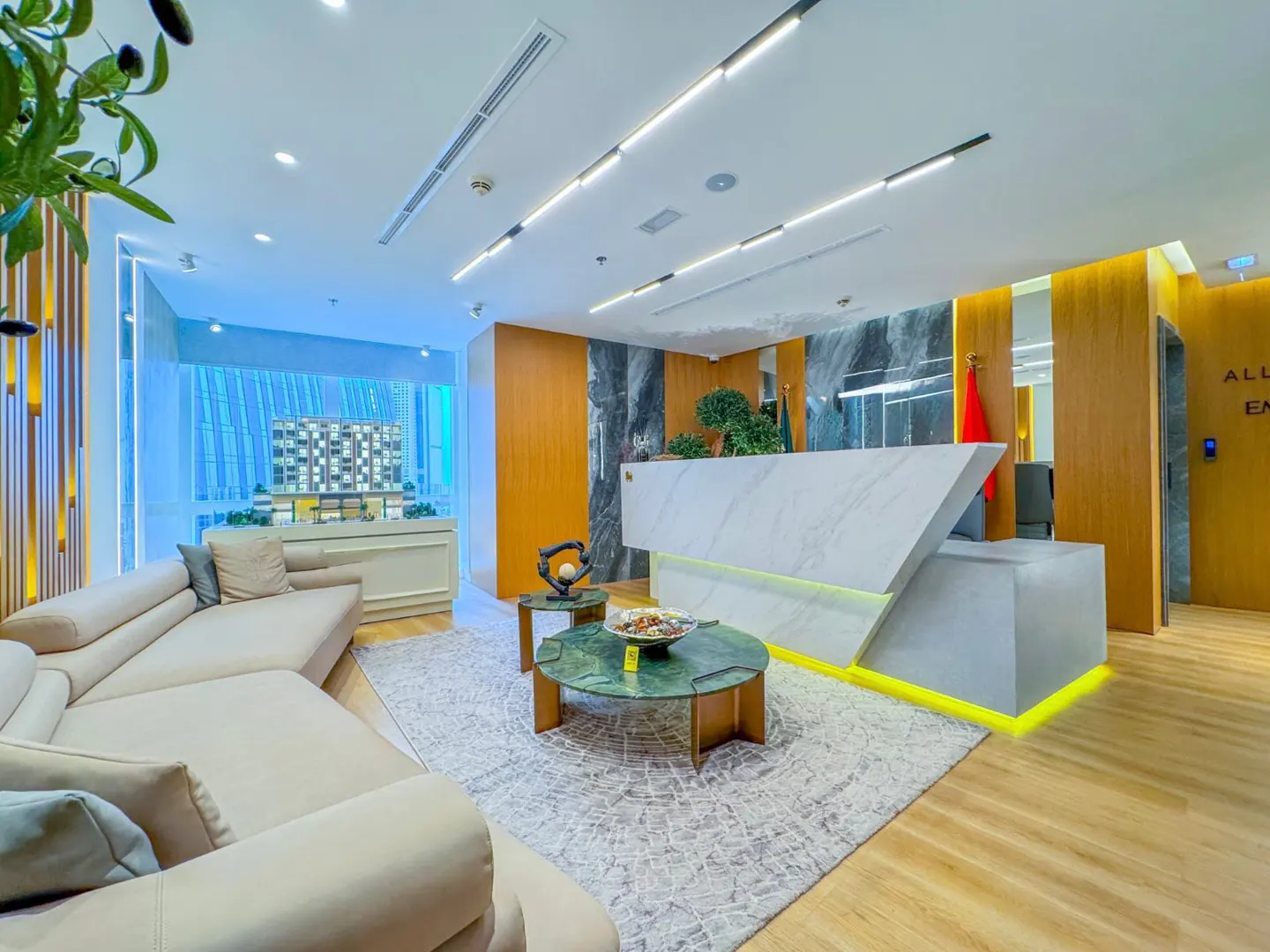 Modern real estate office lobby with a beige sofa, green marble coffee table, and a white marble reception desk.