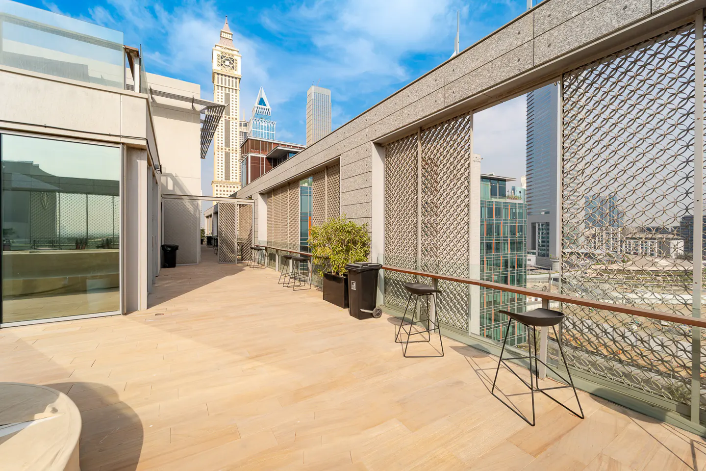 Outdoor patio with beige tile flooring, metal stools, and a view of the city skyline.