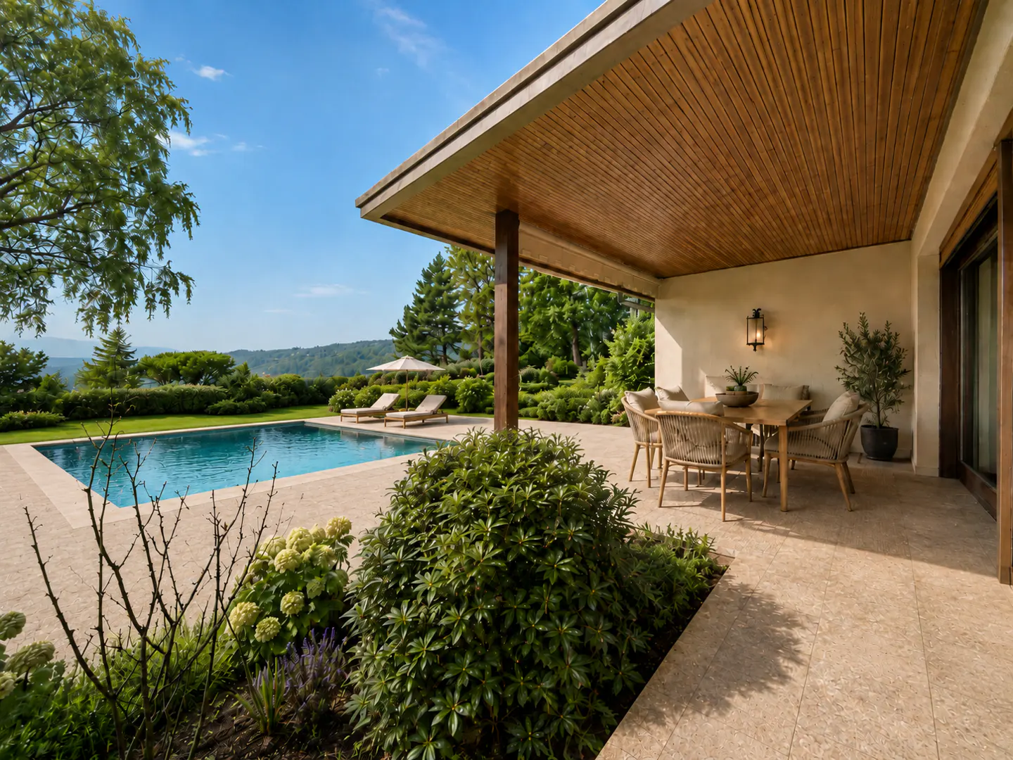 Outdoor patio with a wood ceiling, table, and chairs next to a pool with lounge chairs and green trees.