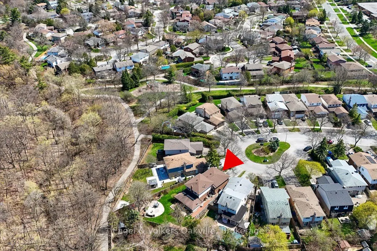 Aerial view of a residential neighborhood with houses, trees, and a red arrow pointing to a specific property.