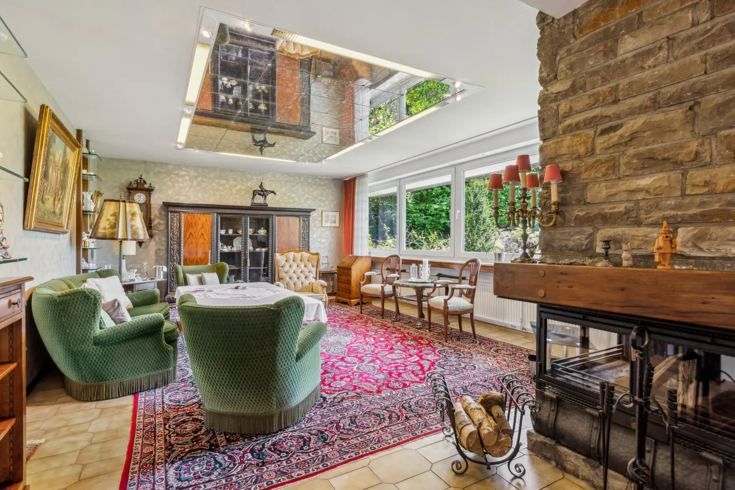 Living room with green chairs, red rug, stone fireplace, and mirrored ceiling reflecting the room.