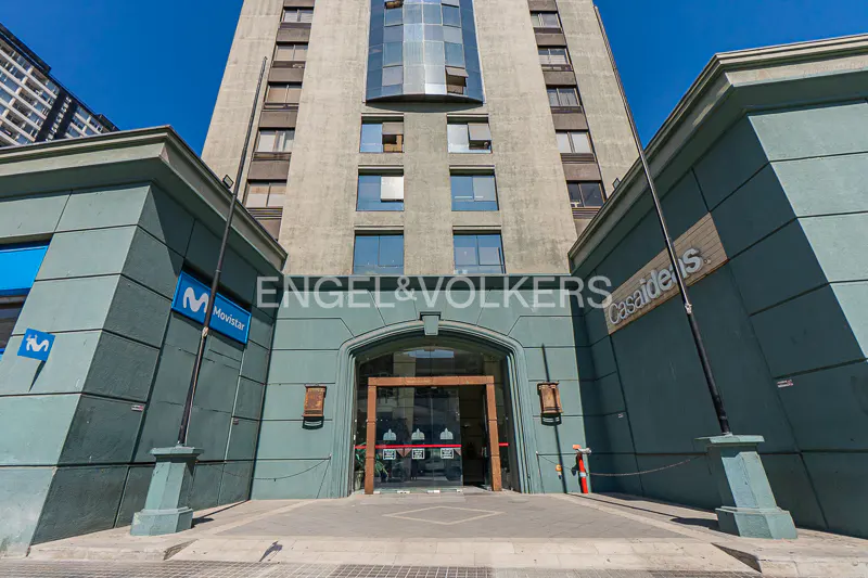 Exterior shot of a tall building with a glass entrance. The building has the Engel & Volkers logo on it. There is a Movistar sign on the left side of the building.