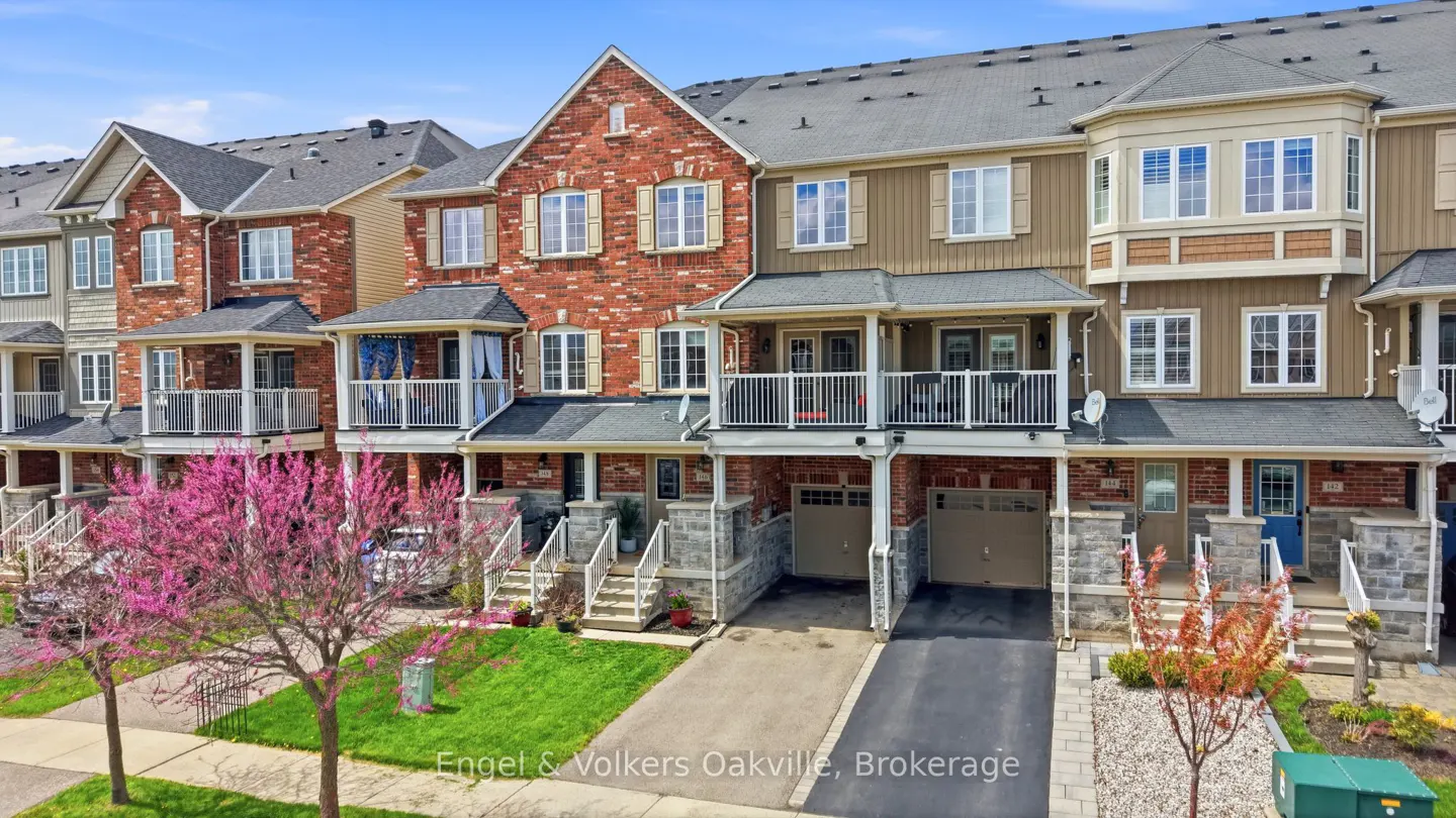 Row of townhouses with brick and siding exteriors, small balconies, and attached garages. Pink flowering trees in the front yard.