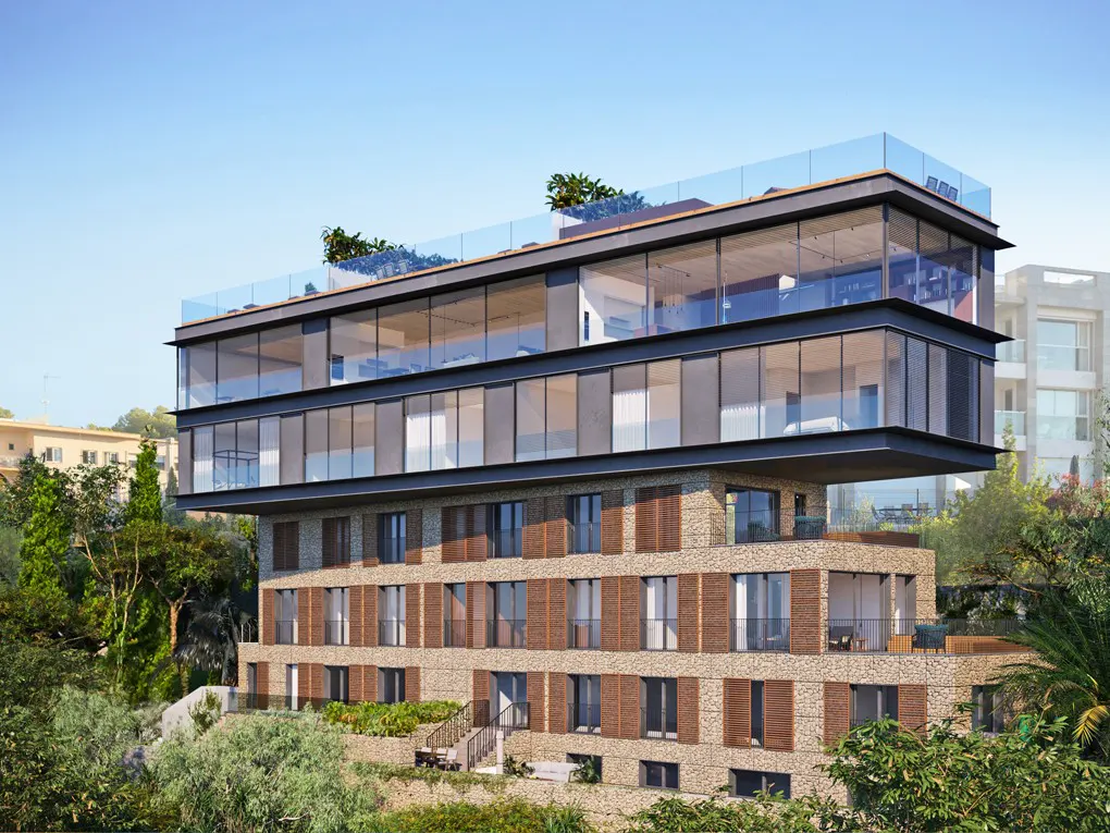 Modern building with stone base and glass upper floors, surrounded by green trees under a blue sky.