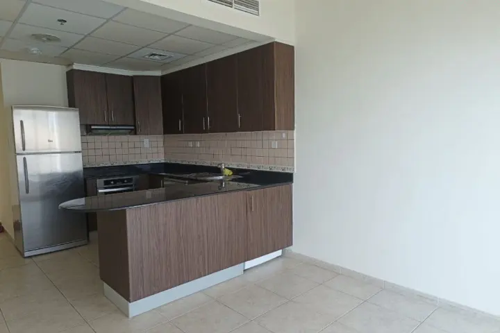 A kitchen with brown cabinets, a stainless steel refrigerator, and a black countertop.