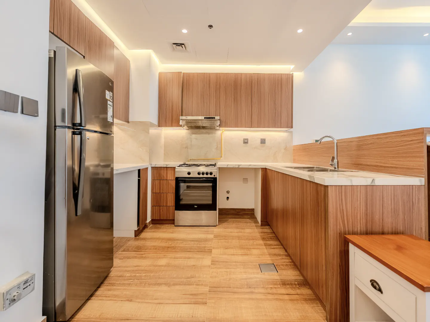 A modern kitchen with wood cabinets, stainless steel appliances, and marble countertops.