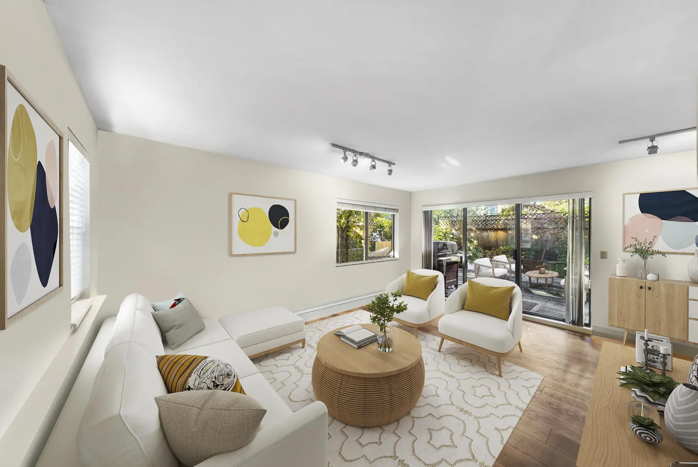 Bright living room with white sofa, chairs, and patterned rug. Sliding glass doors open to a patio with outdoor furniture. Abstract art adorns the walls.