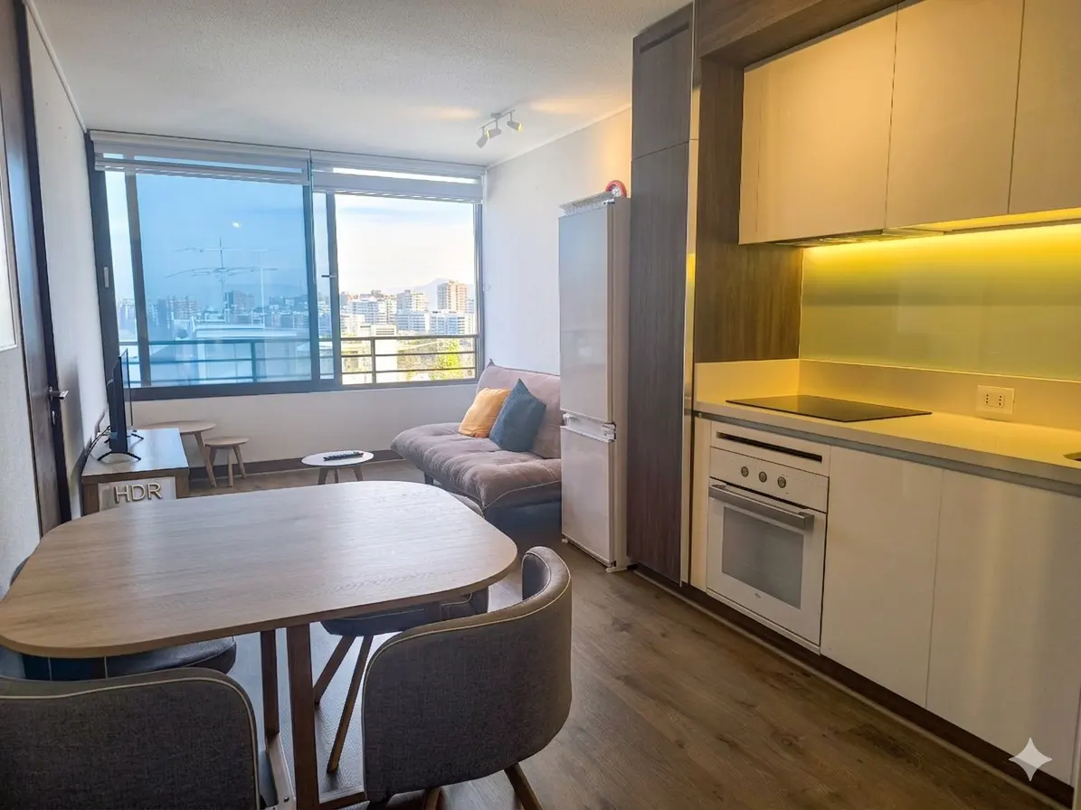 A modern apartment interior with a dining table, sofa, and kitchen area. A large window offers a city view.