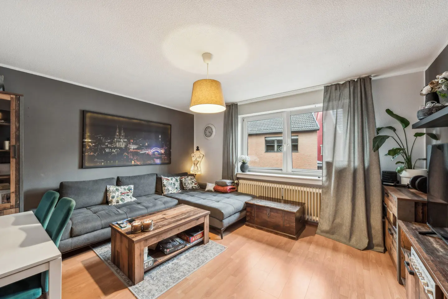 Living room with gray sectional sofa, wooden coffee table, and hardwood floors. A large city print hangs on the gray wall.