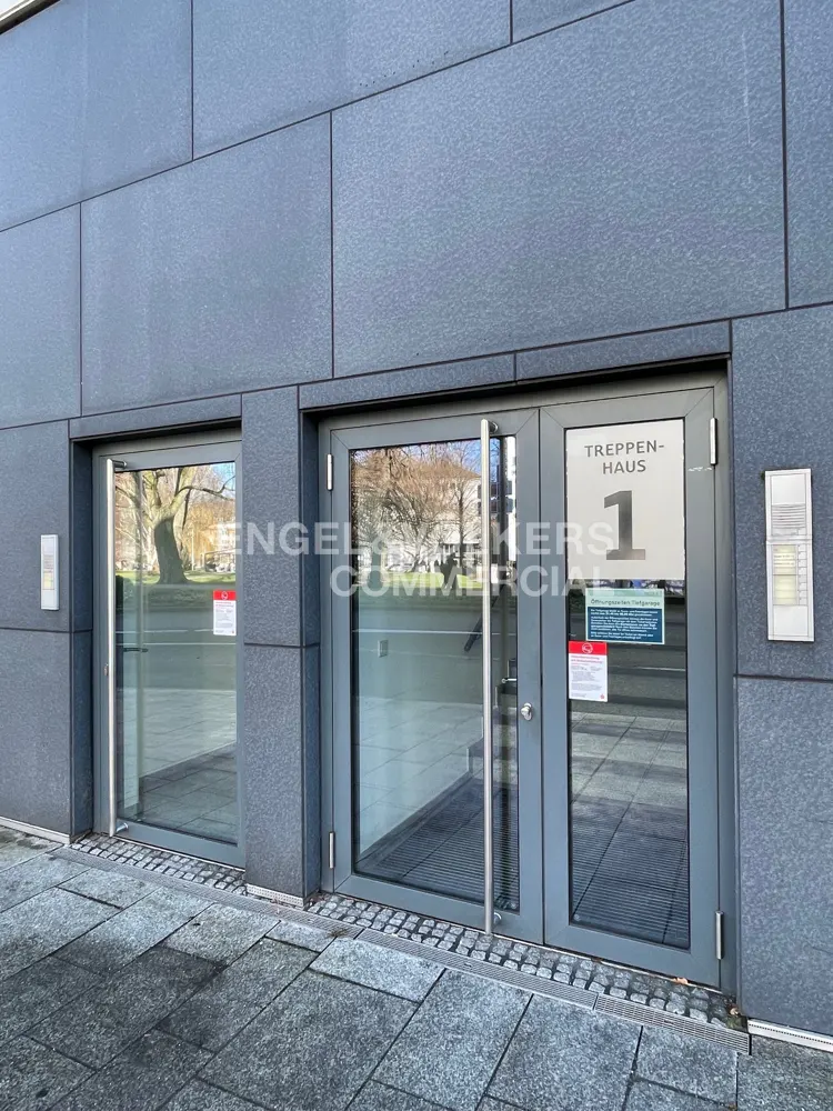 Exterior view of a gray building with two glass door entrances, labeled "Treppenhaus 1".