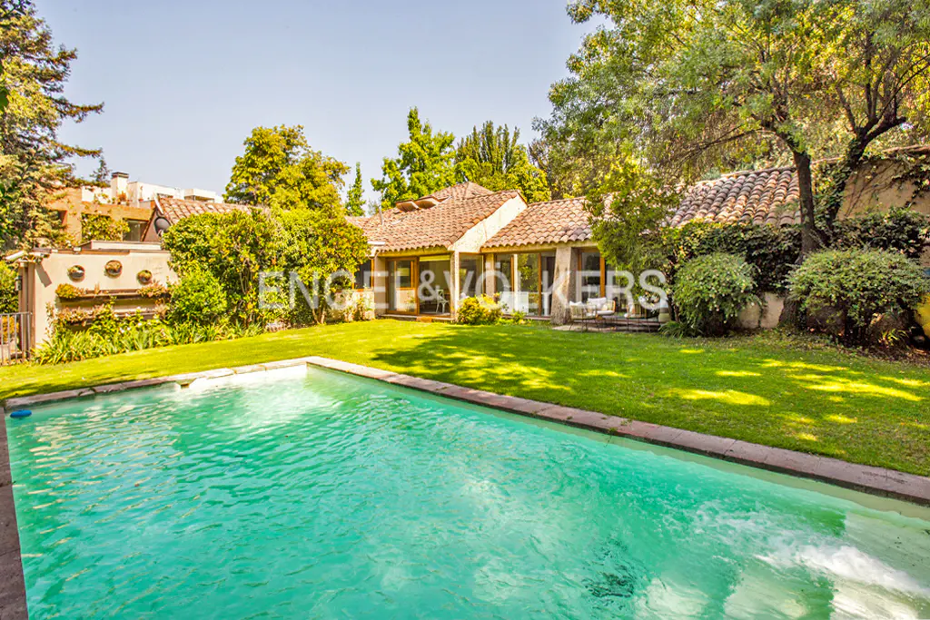 A backyard with a turquoise pool, green grass, and a tan house with a red tile roof.