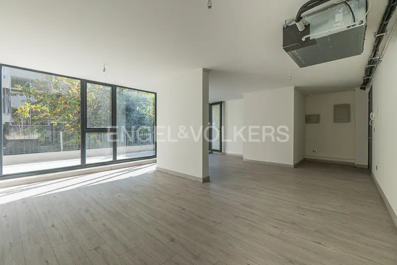 Bright, empty room with light wood floors, white walls, and large windows. An AC unit is visible on the ceiling.