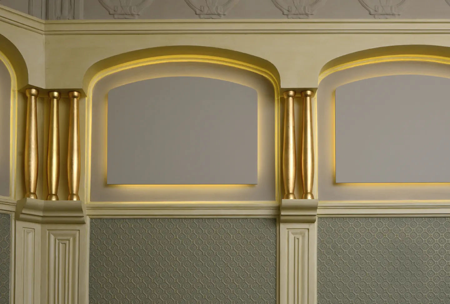 Interior wall with arched niches, gold columns, and patterned wallpaper.