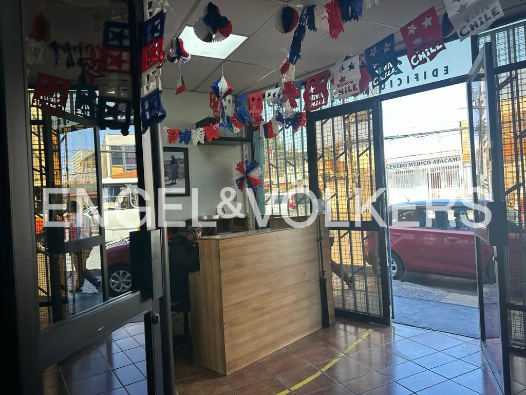 Engel & Volkers office entrance with Chilean decorations. A wooden reception desk is visible inside. A person sits behind it.
