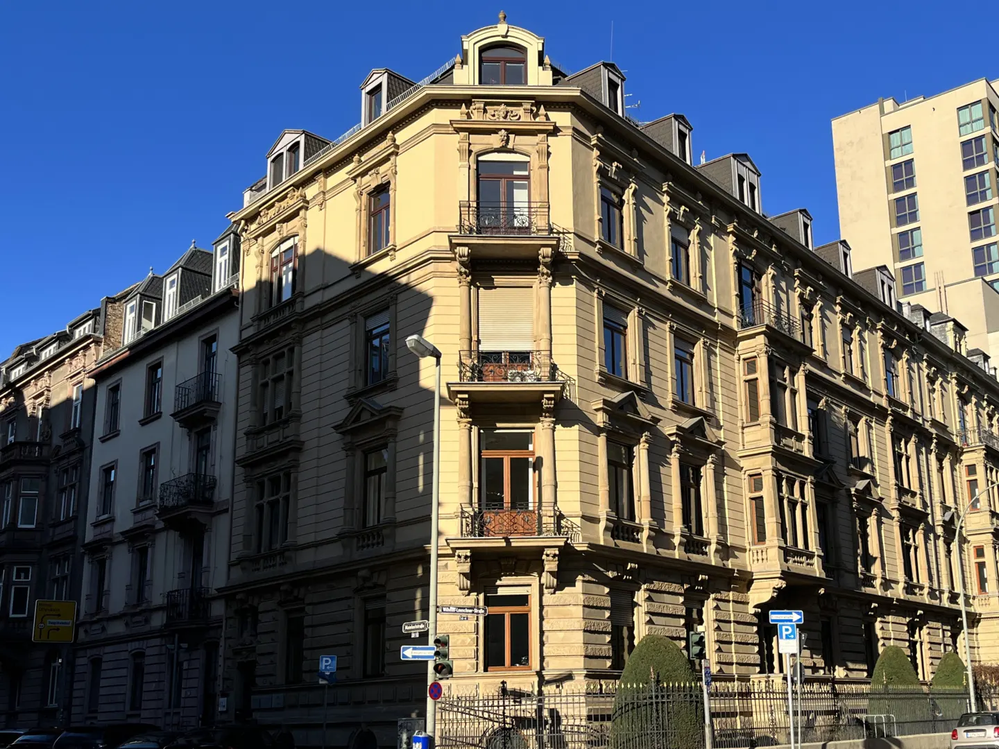 A tan, ornate apartment building with balconies and many windows under a clear blue sky.