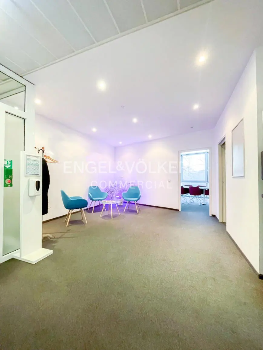 Bright office space with blue chairs, a white table, and the Engel & Völkers logo on the wall.