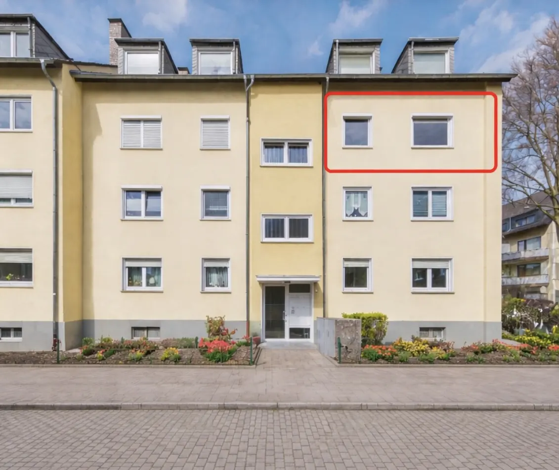 Exterior of a three-story yellow apartment building with white windows and a red outline around the right side of the building.