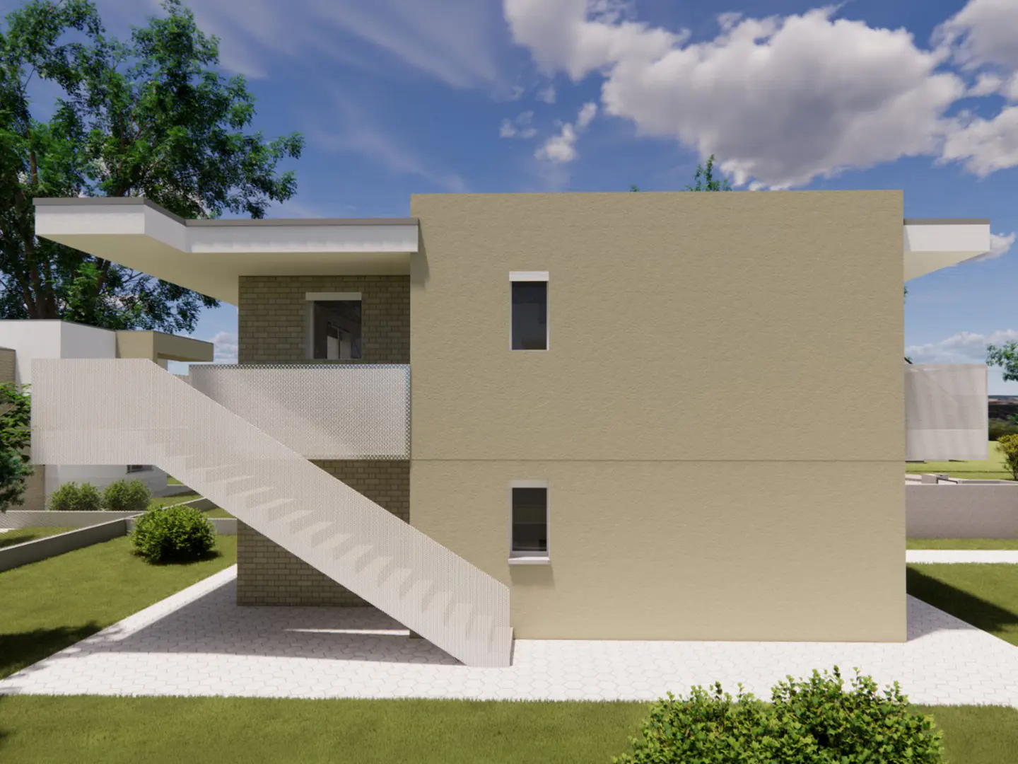 Side view of a two-story tan building with white stairs, small windows, and a brick section. Green grass and trees surround the building.