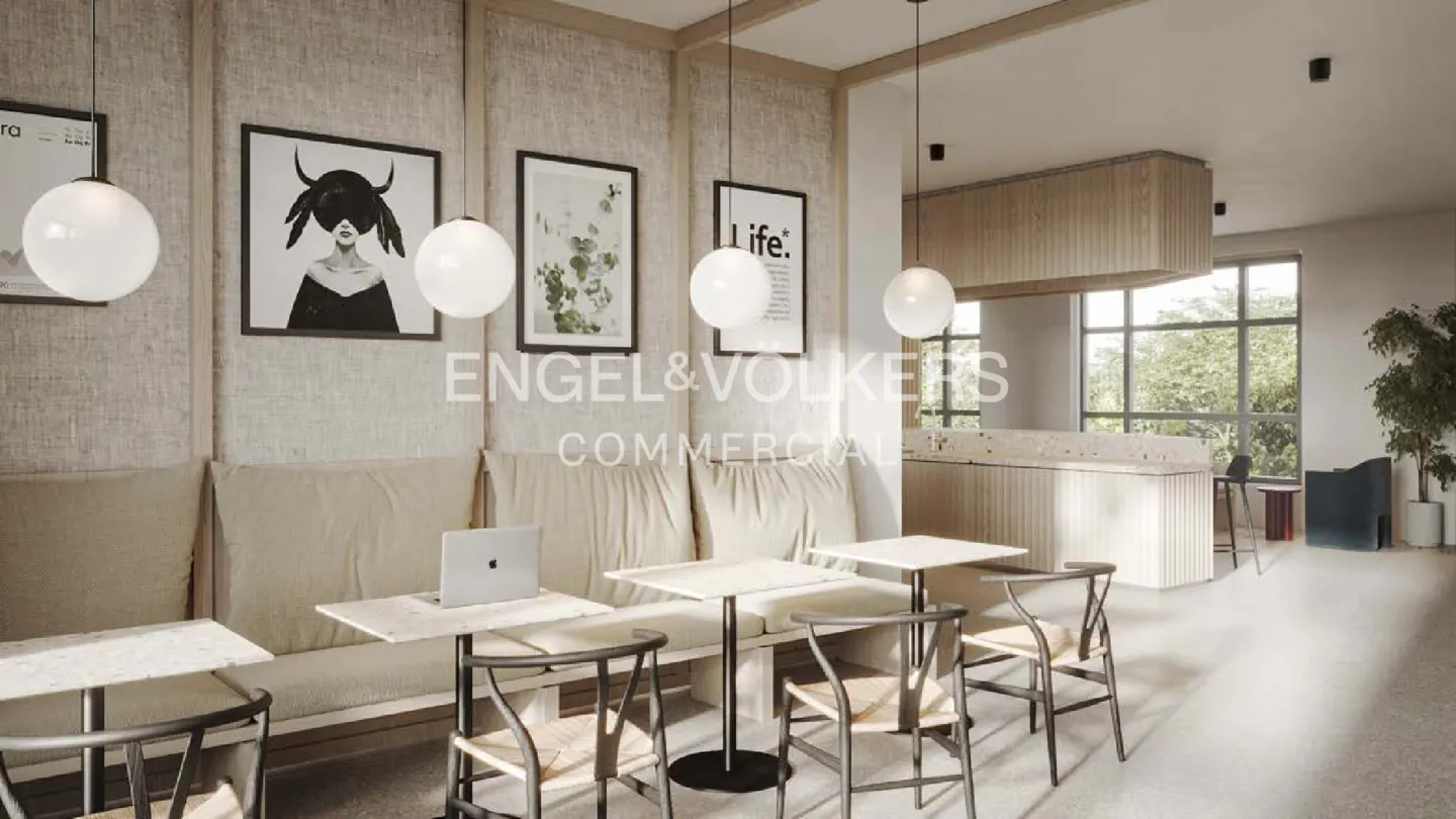 Bright, modern cafe interior with beige seating, square tables, and woven chairs. Globe pendant lights hang above. Laptop on table. Engel & Volkers logo.