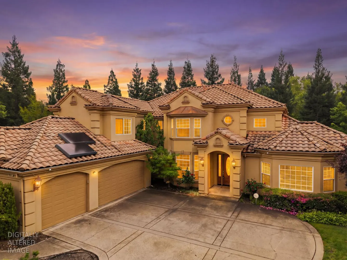 Beige two-story house with a terracotta tile roof, a two-car garage, and a concrete driveway at sunset.