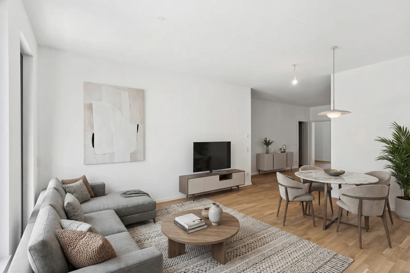 Bright, open-concept living room with gray sectional, round wood table, and marble dining table with chairs. Abstract art on the wall.